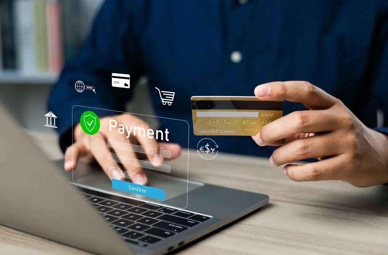Person holding a bank card beside a laptop with an online payment form